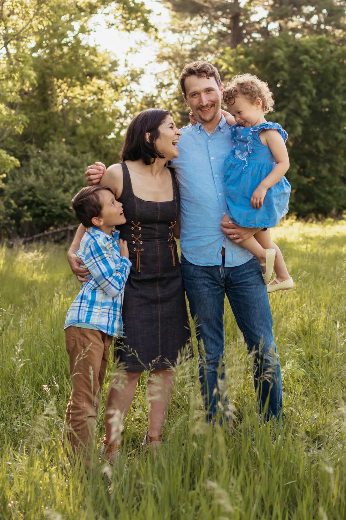 Parents holding their two kids in a sunlit meadow