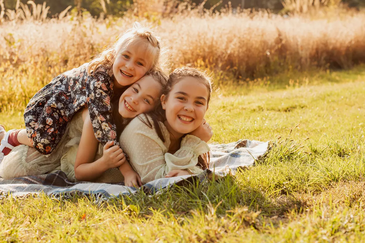 Mom and her two daughters piled together laughing on a blanket