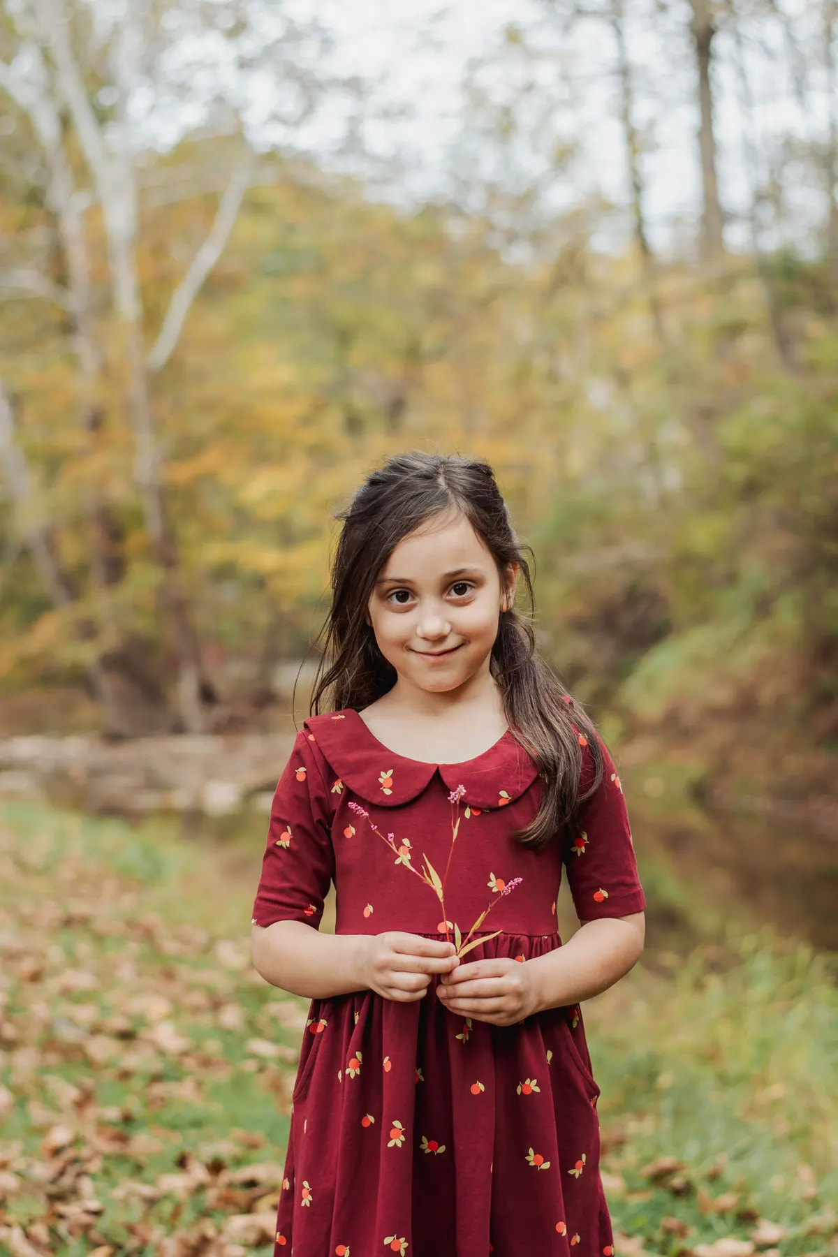 Girl in a red dress standing in fall leaves