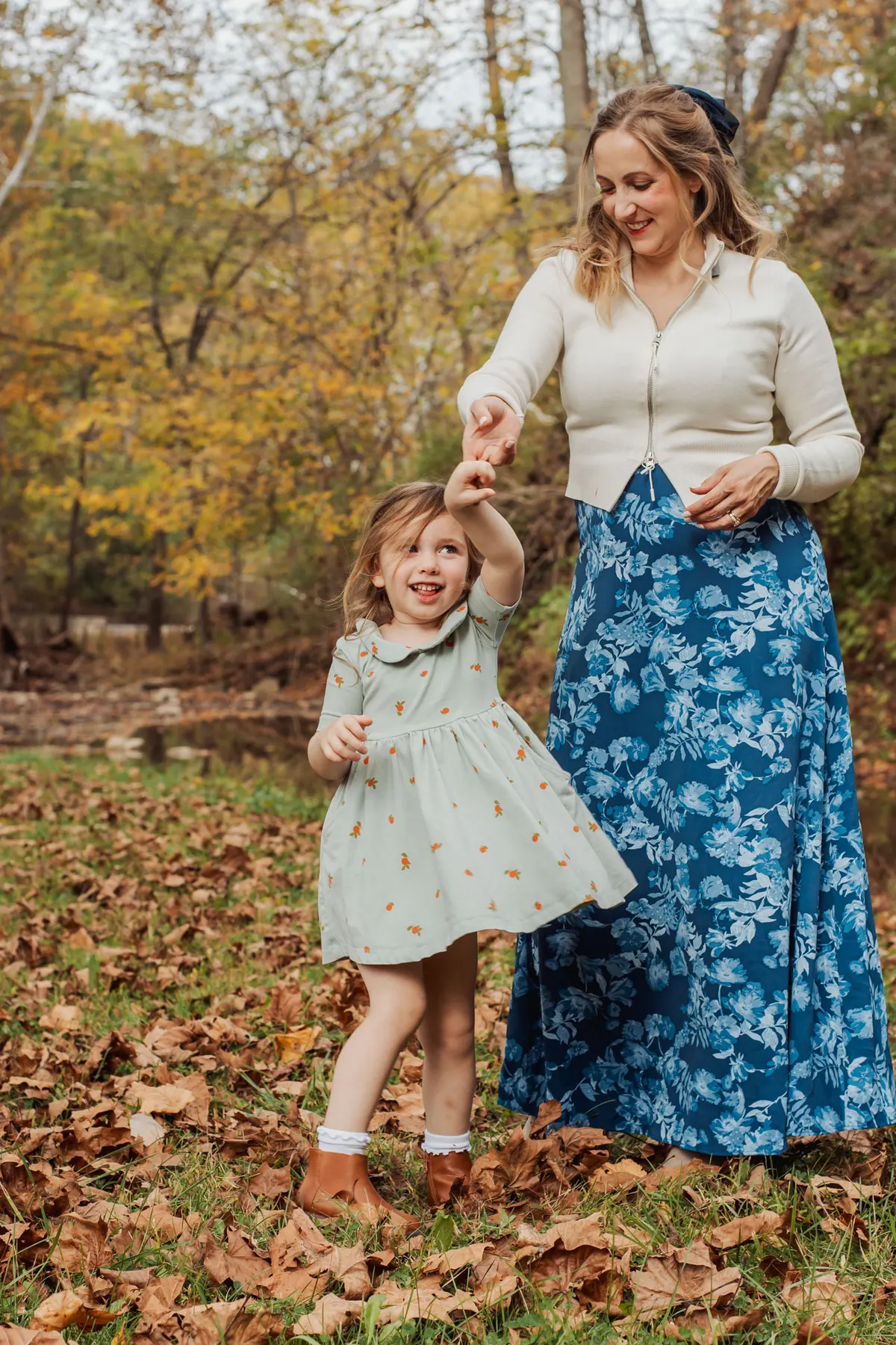 Mom and daughter dancing in fall leaves