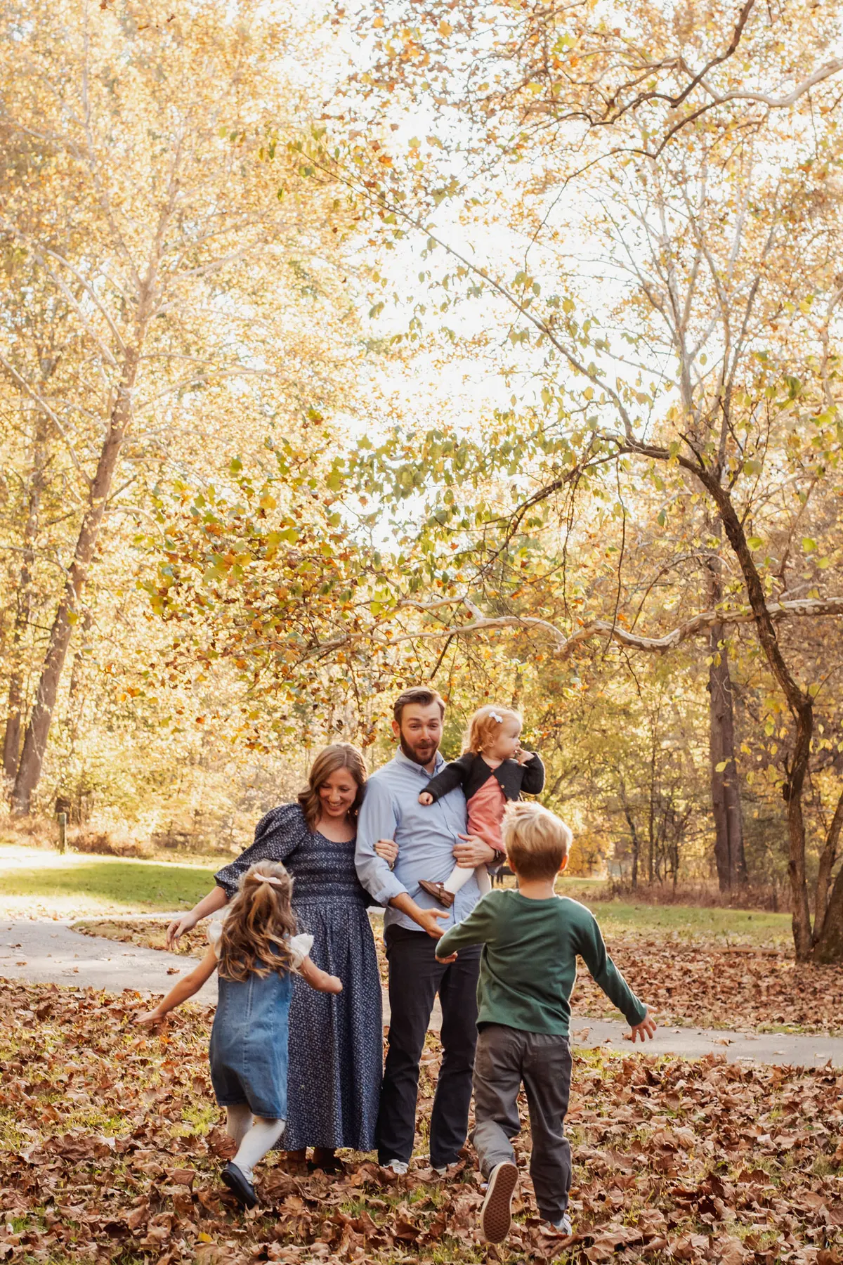 Family running and playing in fall leaves at Mingo Creek Park
