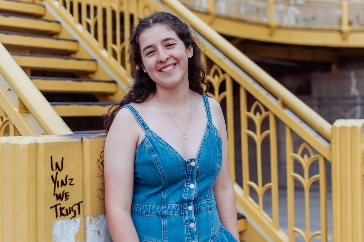 Senior in a denim dress on the yellow bridge stairs in downtown Pittsburgh